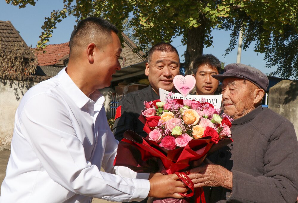 鮮花獻給百歲抗戰老兵王載坤手中。明光市委宣傳部供圖
