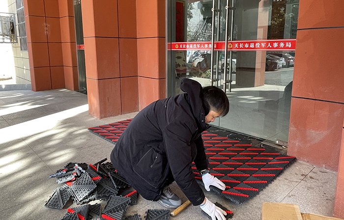 天长市退役军人局组织人员为市局机关大门口铺设防滑垫，方便军人军属前来办理优抚业务。曹基摄