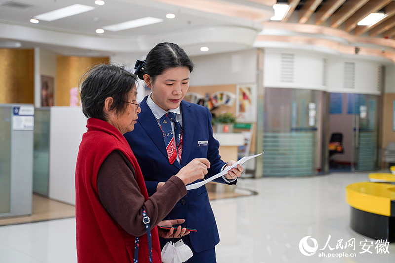 杜怏（右）在为客户介绍金融产品。人民网记者 王锐摄