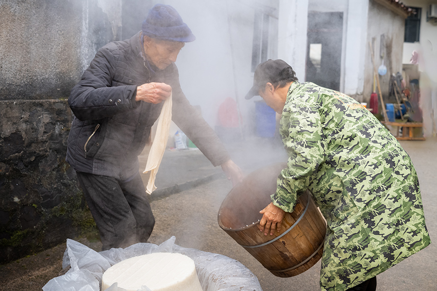 將滿滿一甑子糯米飯倒在石臼中。張余才攝