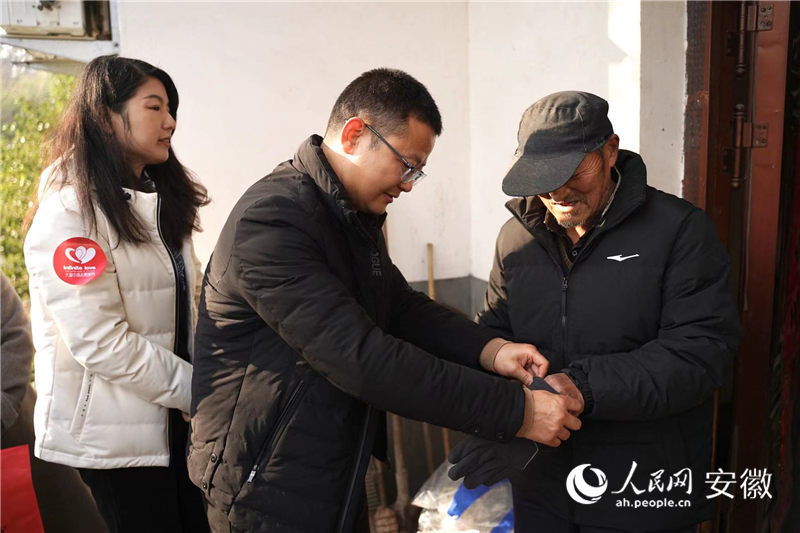 志願者為余有山披上新買的羽絨襖。人民網記者 王銳攝