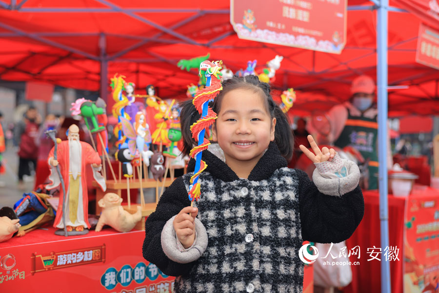 一位小女孩在面塑攤挑選到心儀的“龍”，笑成了一朵花。人民網記者 王曉飛攝