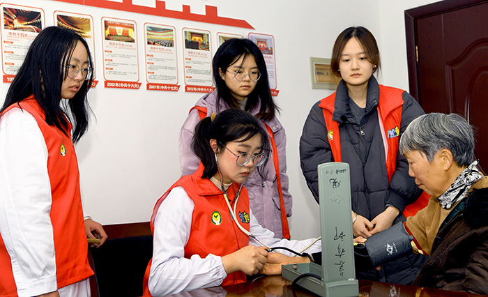 1月21日，蚌埠医科大学精神卫生学院4名大学生志愿者正在为村民量血压，并向他们宣讲健康知识，祝村民过一个健康祥和的龙年春节。