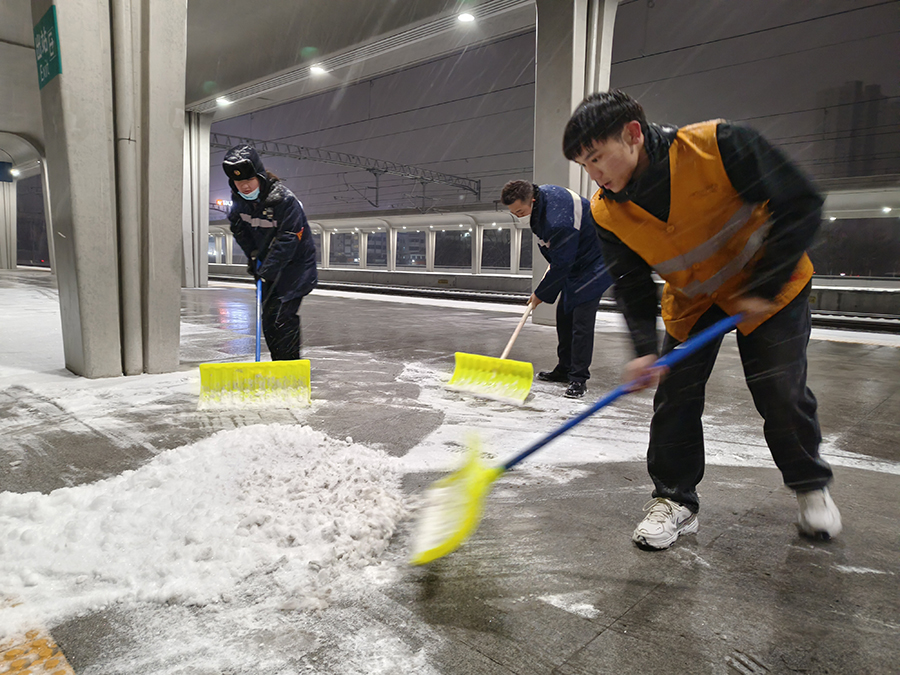 工作人員深夜清掃站台積雪，為雪夜旅客出行鋪設安全通道。宿州火車站供圖