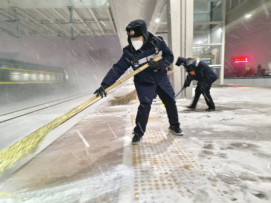 工作人员深夜清扫站台积雪，为雪夜旅客出行铺设安全通道。宿州火车站供图