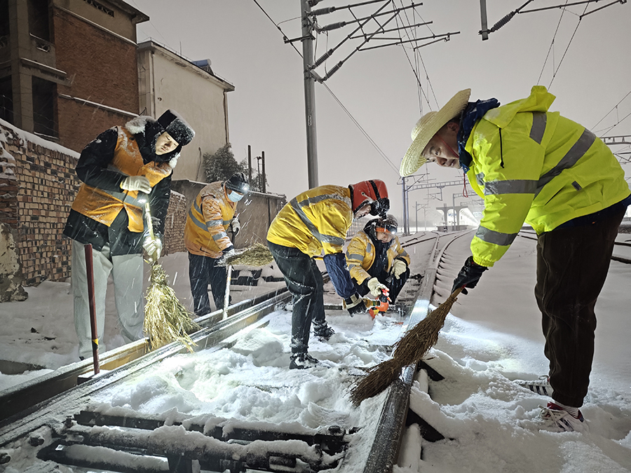 扫雪突击队员子夜冒雪清扫道岔积雪保列车安全畅通。宿州火车站供图