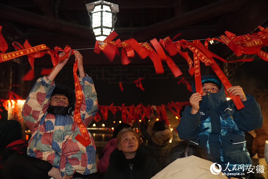 两个小朋友在家人的陪伴下系红绳祈福。人民网记者 陈若天摄