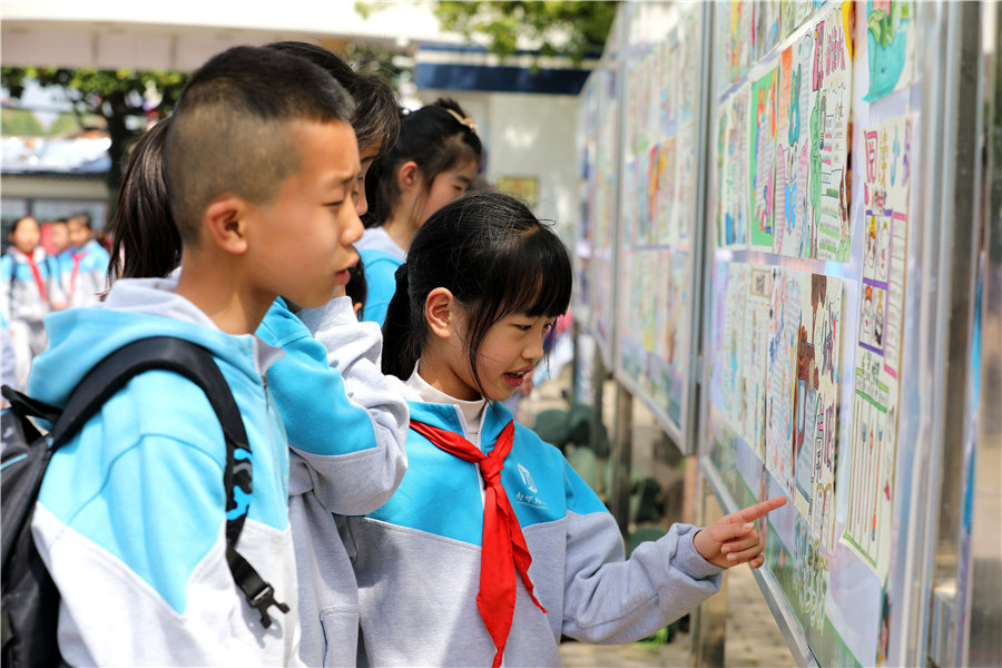 同学们在学校读书长廊里观看“手抄报”。