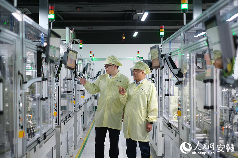 周奇文（右）向科技银行客户经理介绍公司生产线。人民网 胡雨松摄