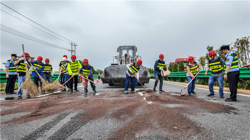 公路养护人员及时清理清运现场洒落建材，利用沙石清理了桥面油污。人民网记者 陶涛摄