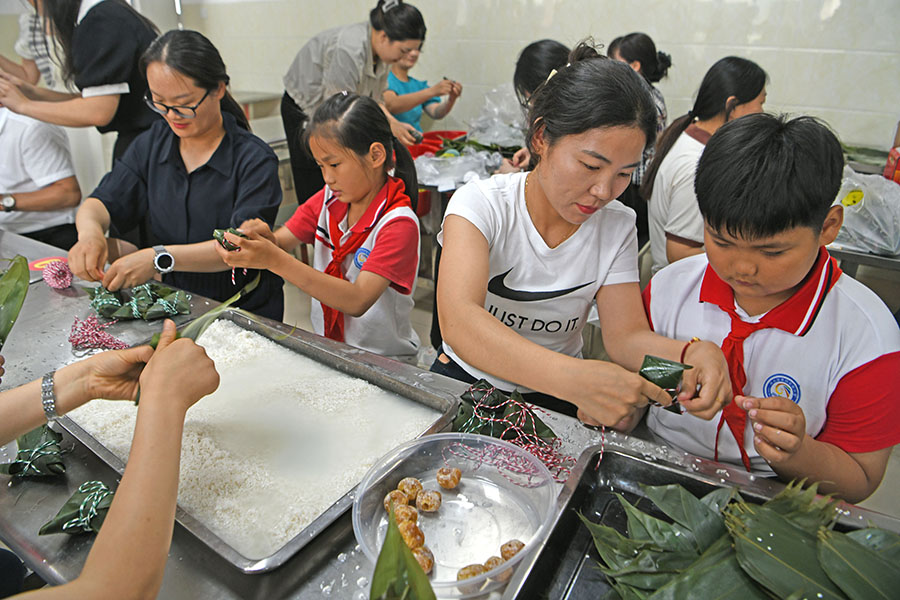 2024年6月6日，安徽省淮南市凤台县第四实验小学学生在老师的指导下学习包粽子。