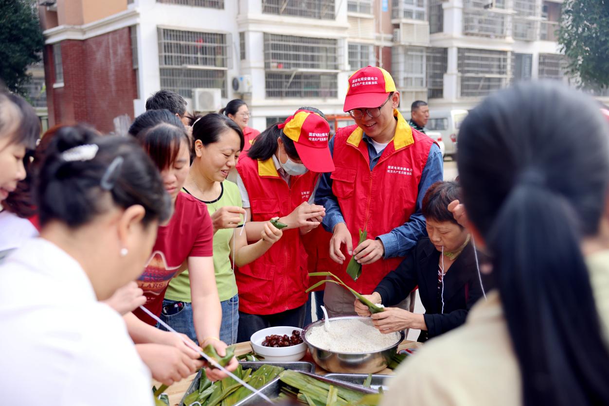 志愿者与小区老人们围坐在一起包粽子。周里摄