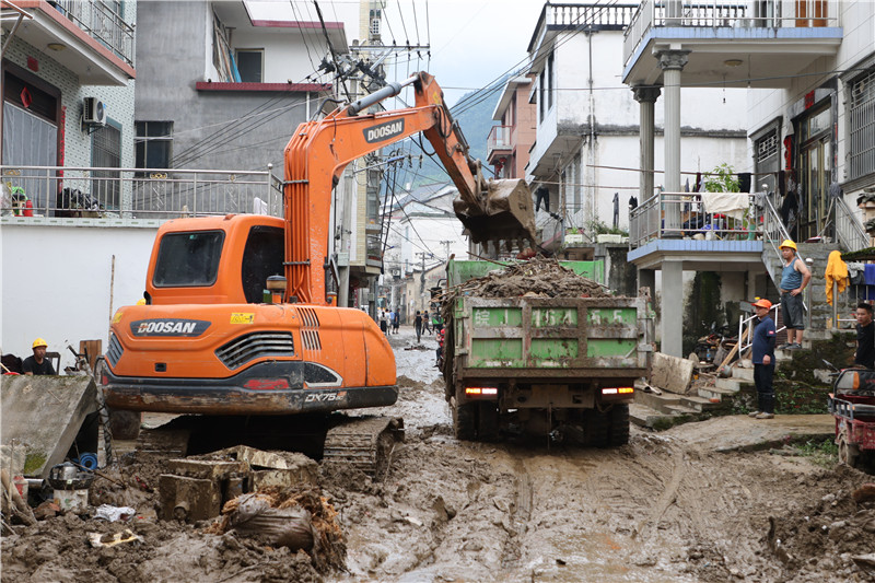 大型工程车辆正在满是泥泞的街道上开展清淤作业。人民网记者 王晓飞摄