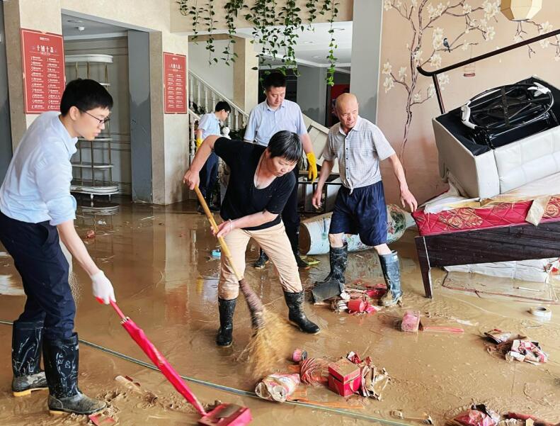 歙县农商银行协助群众开展灾后清理。
