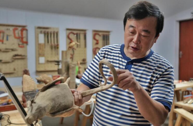 靳朝晖在介绍竹木根雕作品。程力摄