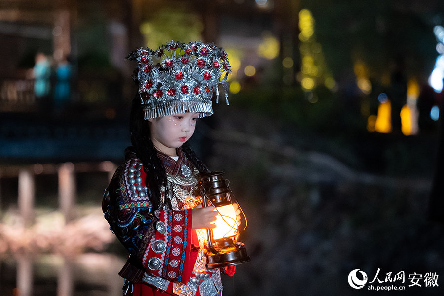 前来游玩的小朋友身着苗族特色服饰在景区内打卡拍照。人民网记者 涂敏摄