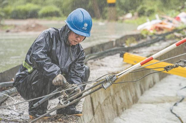 供電員工在大雨中緊固10千伏一心線電杆拉線。