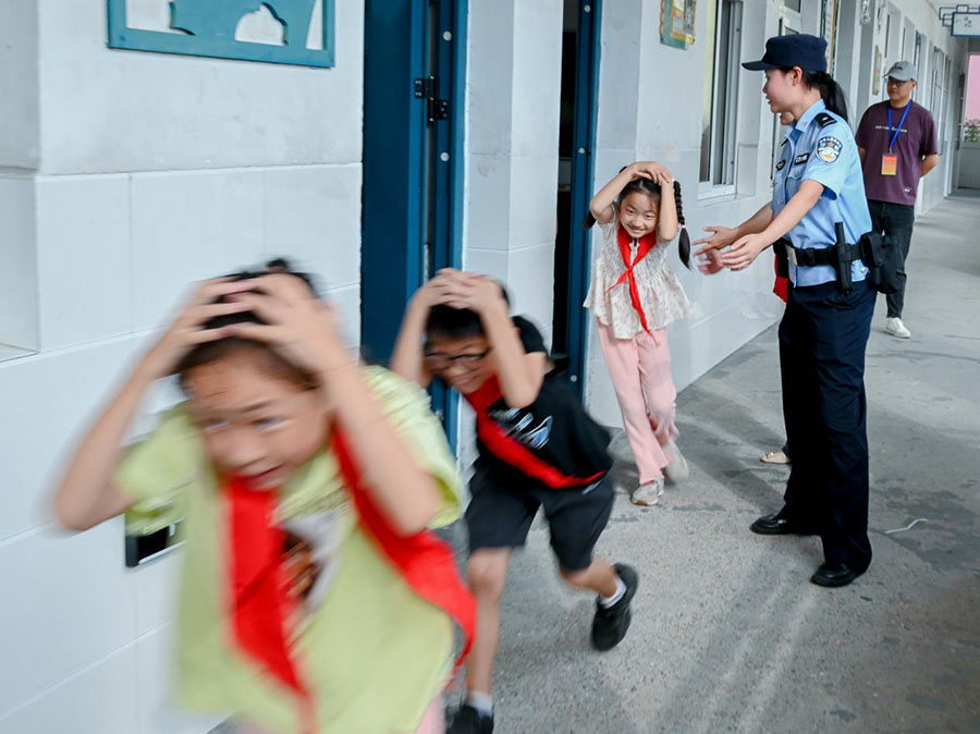 民警与志愿者对学生开展地震避险逃生演练。