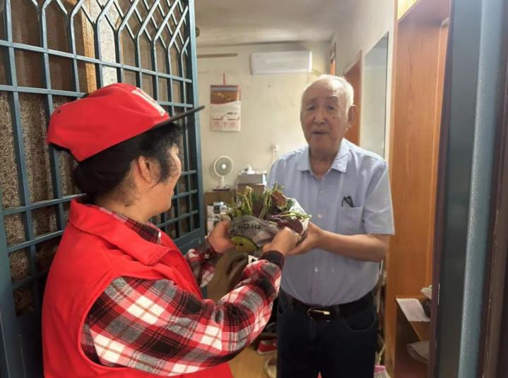 和平路街道小區居民活動中心志願者為轄區高齡老人送菜。