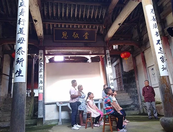 乡贤在给村中少年和到访的国际友人讲解家风家训。纪雯缕供图