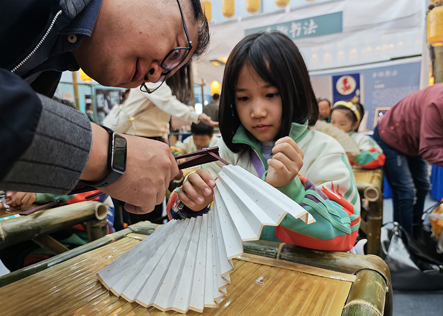 家長陪著孩子在制作折扇。