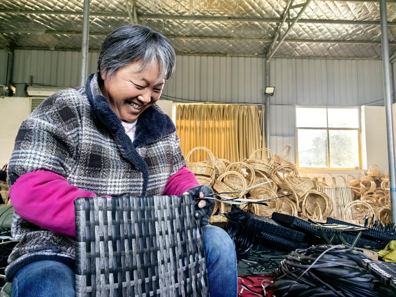 劉國榮在家門口的工廠開心地編著竹籃