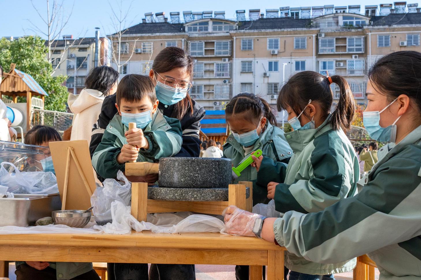 孩子们跟社区志愿者学习石磨自种芝麻粉