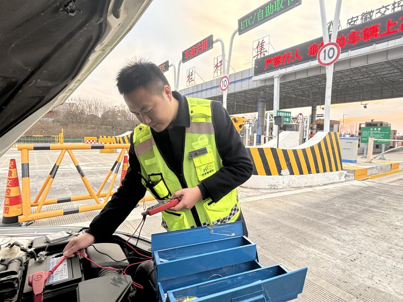 皖通公司合肥处栏杆集站收费员晋鑫帮助驾驶员检修车辆。合肥处供图