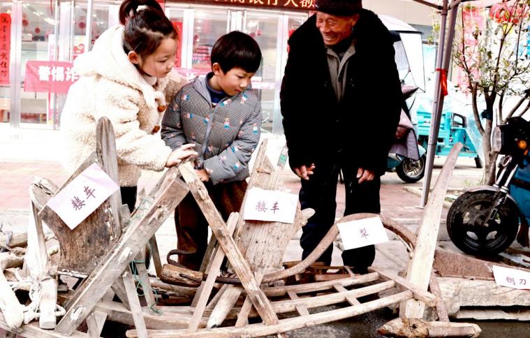 村民义务讲解传统农具，让孩子了解传统农耕文化。张雪芹摄
