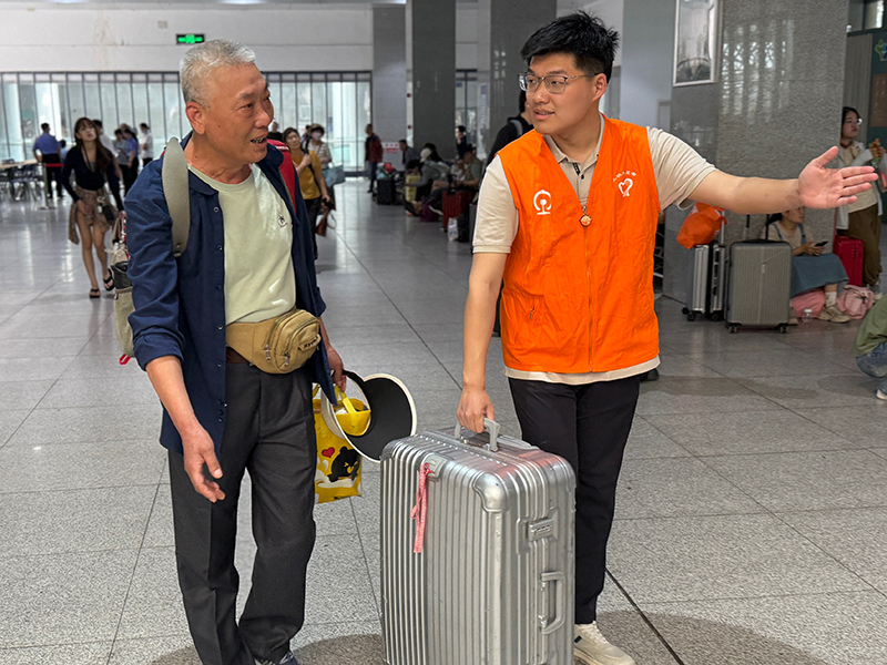 大学生志愿者宁子翔在蚌埠火车站为旅客指引。孟婧雅摄