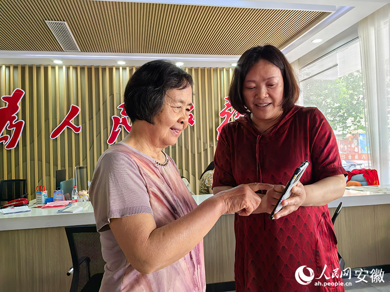 社区工作人员张雨在向群众介绍“无感互认”。人民网记者 韩震震摄