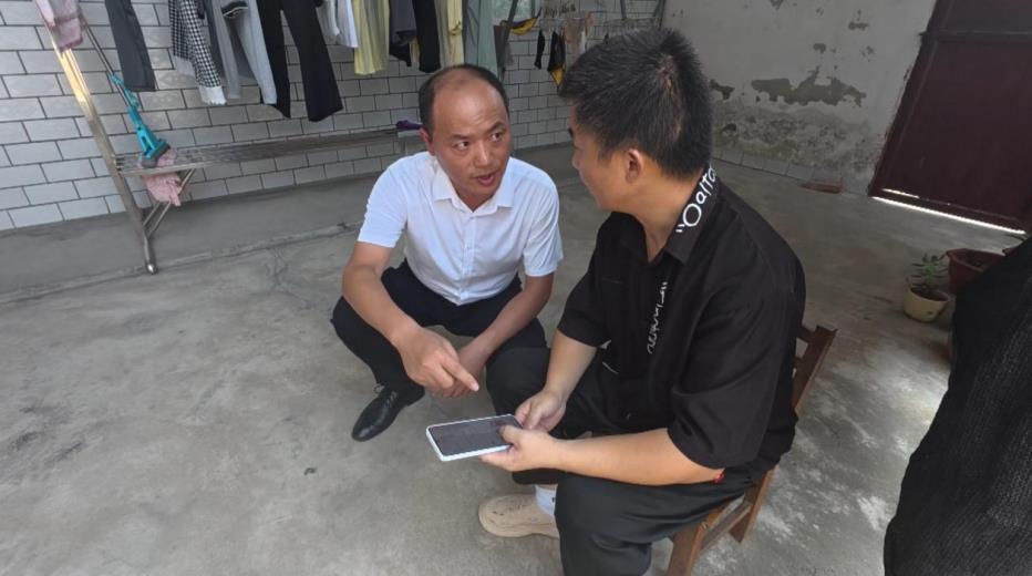 新安镇工作人员指导残疾人王务成在手机上办理业务。赵宇摄