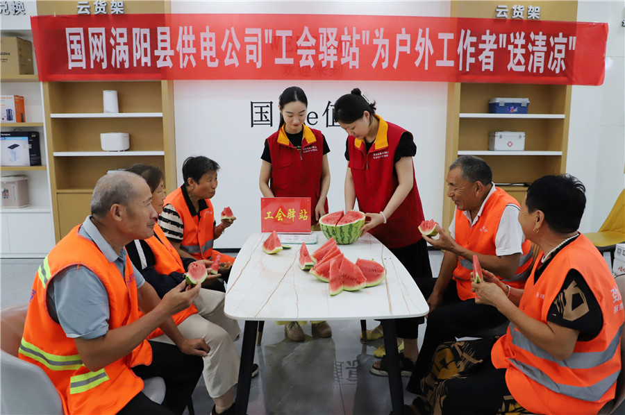 在国网涡阳县供电公司建设路营业厅“电力工会驿站”，工作人员为环卫工人送上西瓜解暑降温。