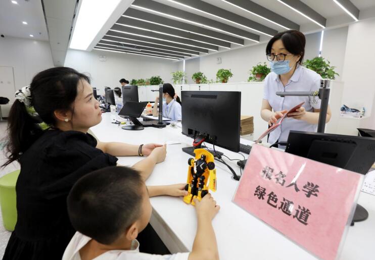 工作人員在“綠色通道”為新生入學報名群眾辦理不動產登記業務。李鑫攝