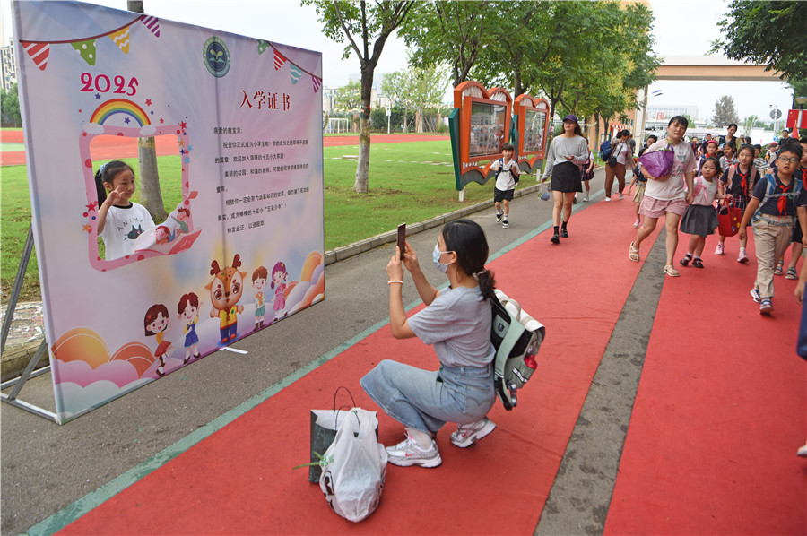 安徽省淮南市淮师附小山南第十五小学一年级新生在入学证书展板前拍照留念，迎接新学期到来。