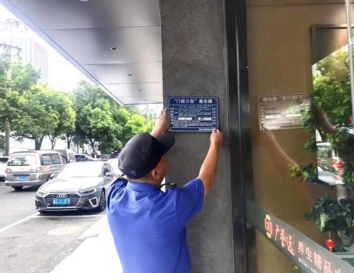 稻香村街道城管隊員在轄區商業樓宇粘貼”門前三包“責任牌。