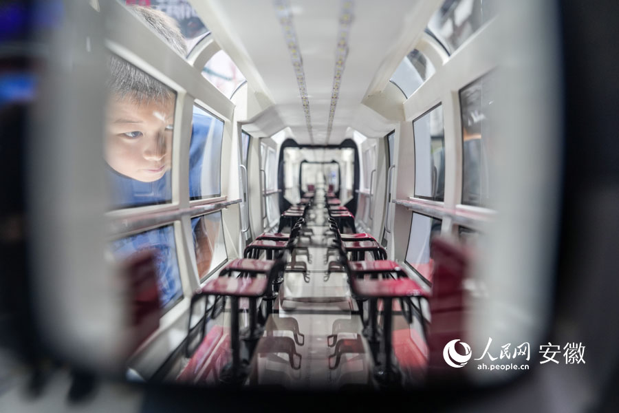 市民透過車窗觀察中國中車吊軌列車模型內部。人民網記者 苗子健攝