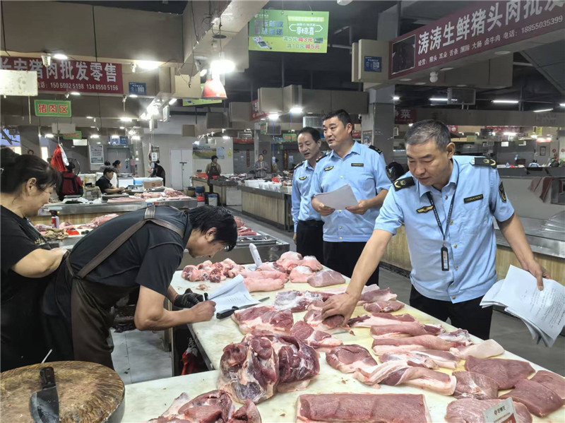 执法人员对猪肉经营户进行检查。