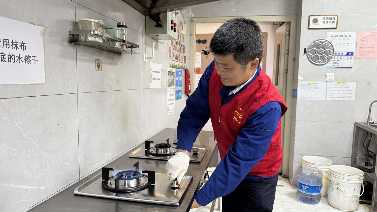 吴雄飞正在调试新灶具。合燃华润燃气供图