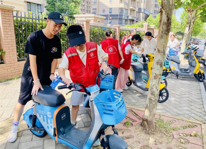 “小小志願者”參與環境整治，有序擺放共享單車。長豐縣雙墩鎮供圖