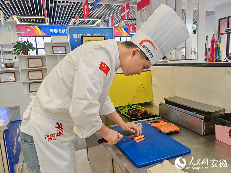 杨萧剑在切三文鱼。人民网 丁纪摄