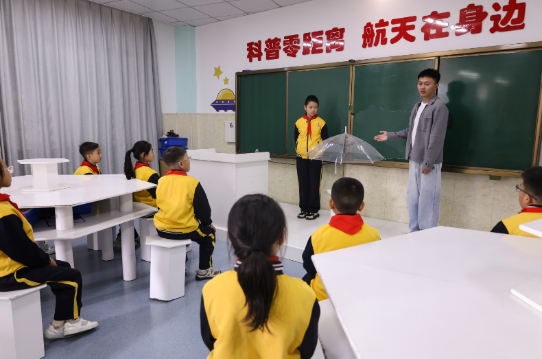 何光鈺正興致勃勃地向同學們展示自己的獲獎作品“智能感應雨傘”。