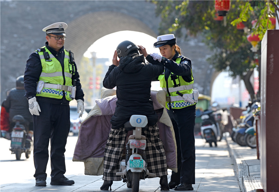 交警金安琪（右一）幫助騎行電動車的市民佩戴頭盔。