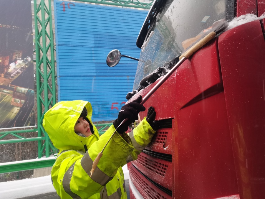 1月20日，芜湖中心芜湖收费站收费员为大货车清扫挡风玻璃与车牌上的雪。