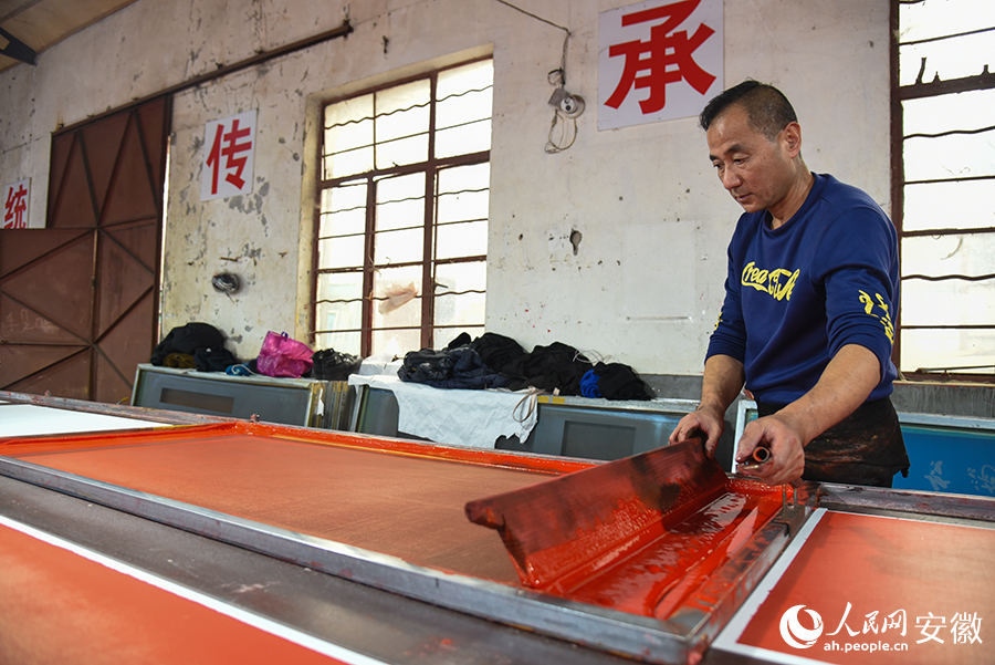 工人正在使用丝网印刷工艺赶制“万年红”春联。人民网记者 李希蒙摄