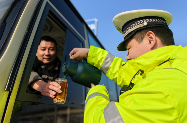 执勤交警为驾驶员添加热水。