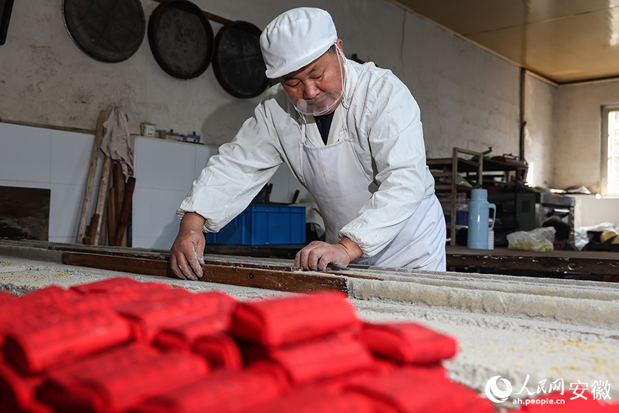 孙鑫平用压板将酥糖坯压制成型。人民网记者 张俊摄