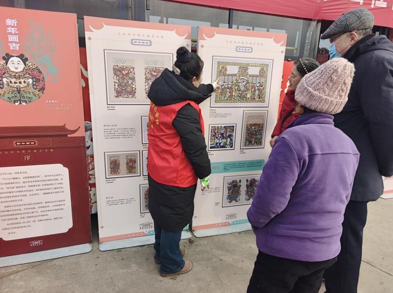 淮北花木文化城公交场站年货大集上，志愿者为市民讲解“新年画吉大运河木板年画艺术展”。