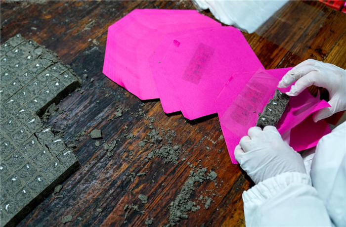 工人将切好的酥糖放入粉色油纸中，进行封装作业。