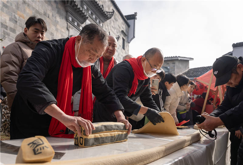 金惠民（前排左一）展示嵌字豆糖制作技艺。胡智华摄